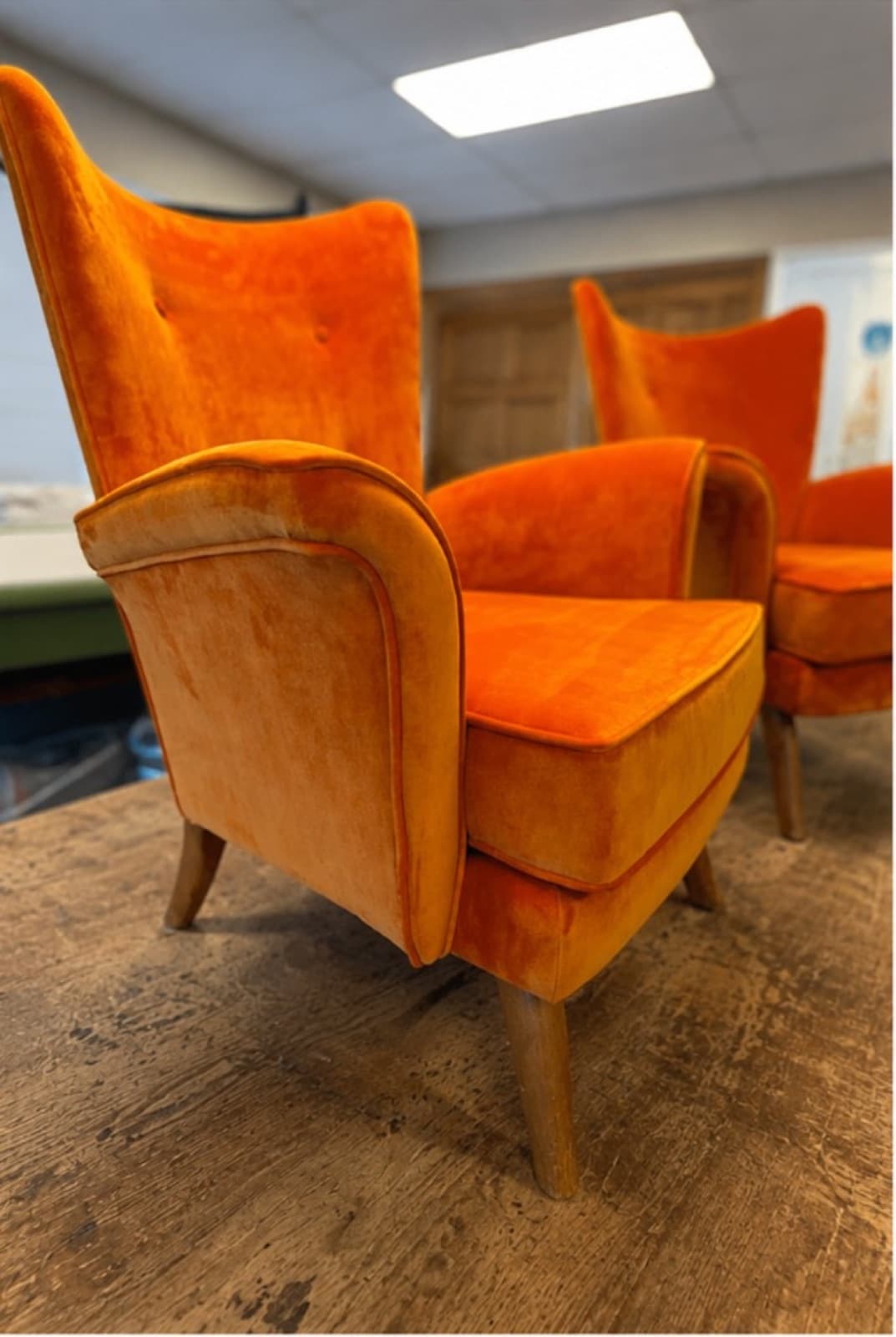 Pair of wingback armchairs reupholstered in bright orange velvet