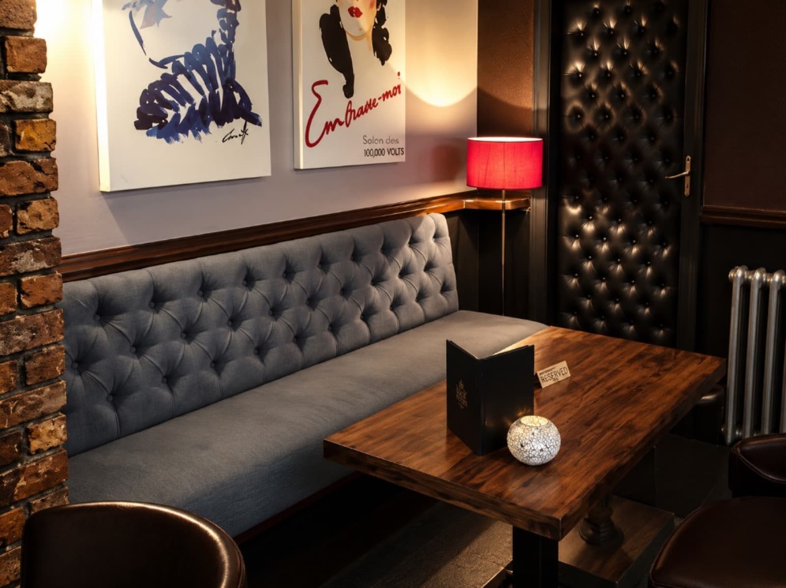 Grey tufted banquet seating and black tufted wall panel in a restaurant