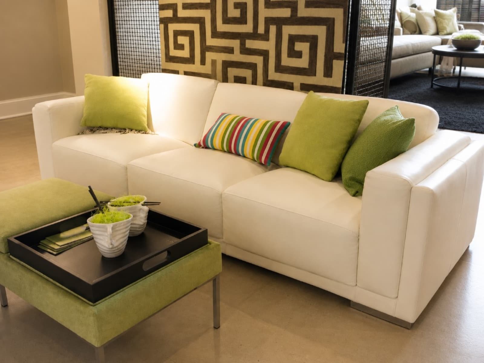 Cream leather sofa with green cushions and pale green ottoman in a modern living room