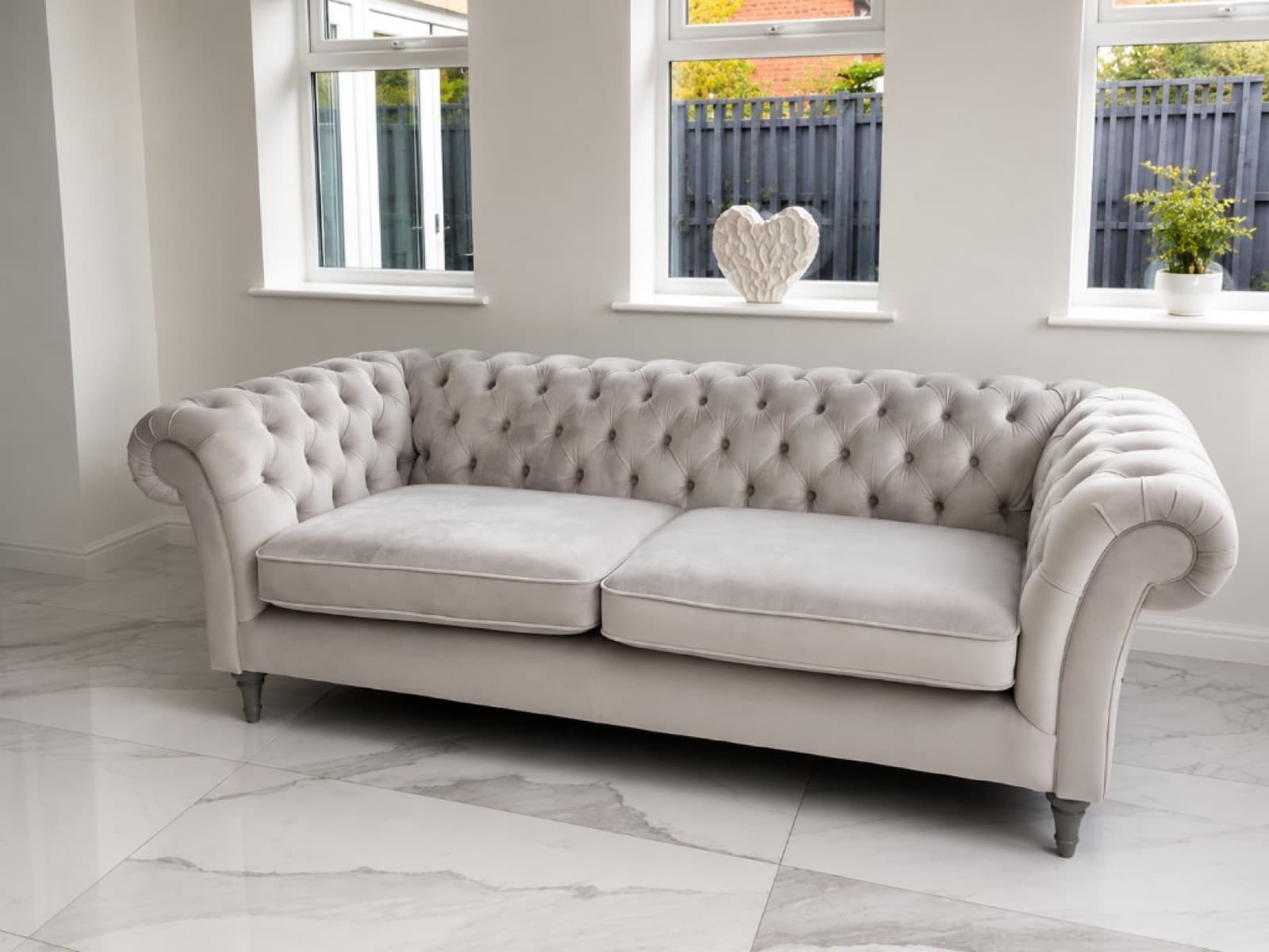 Light grey button-tufted Chesterfield sofa in a bright modern room