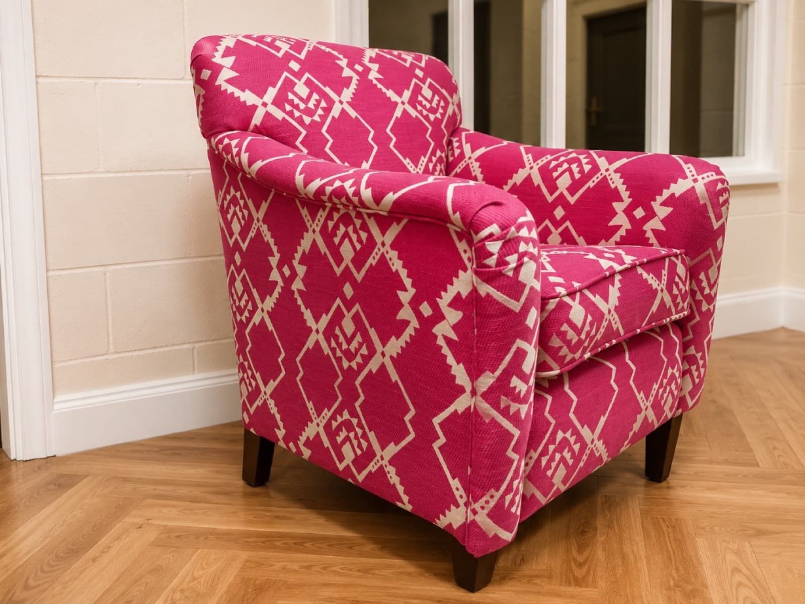 Modern armchair in magenta and cream geometric patterned fabric