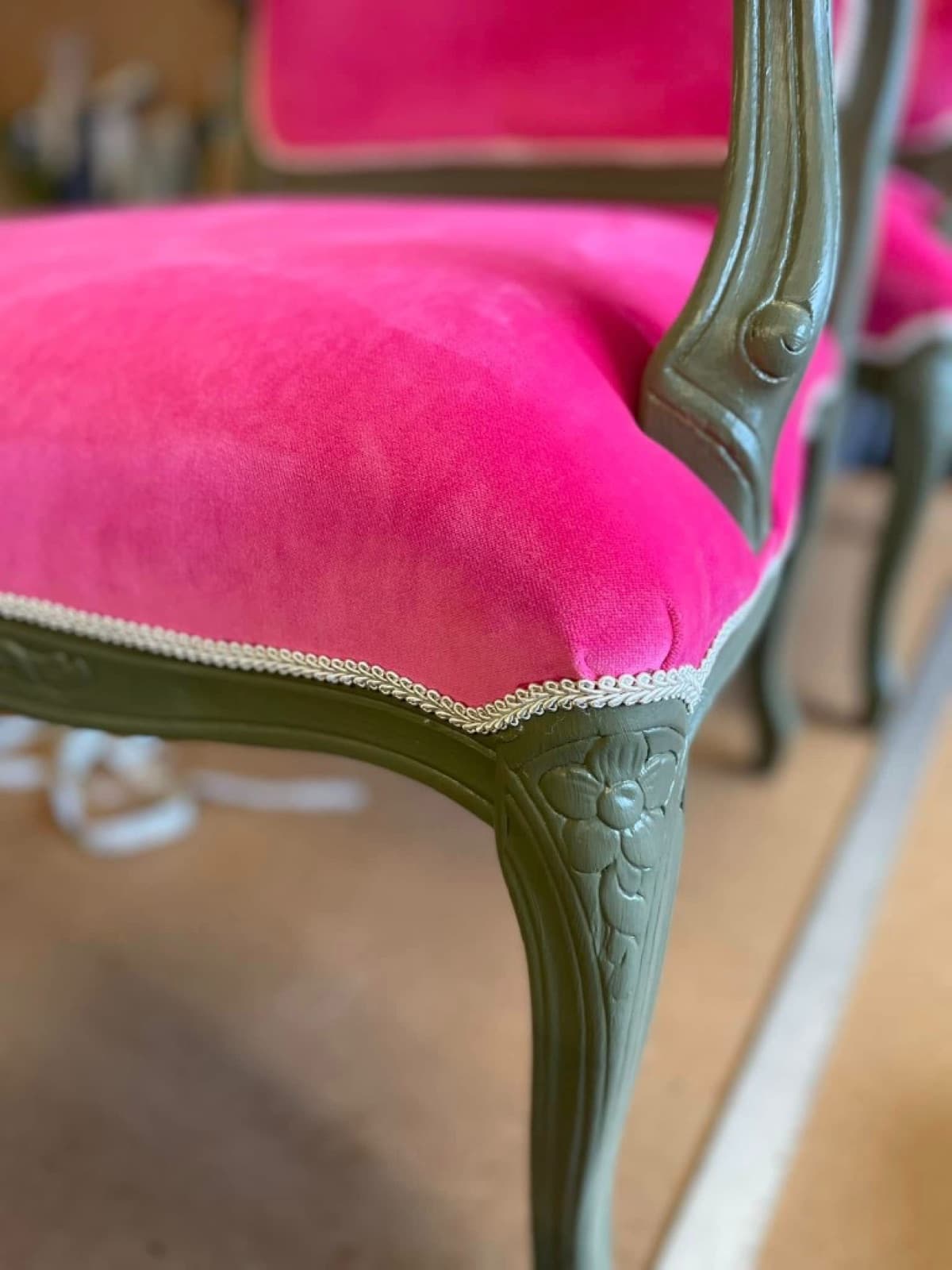 Detail of fuchsia pink velvet seat against a sage green carved frame