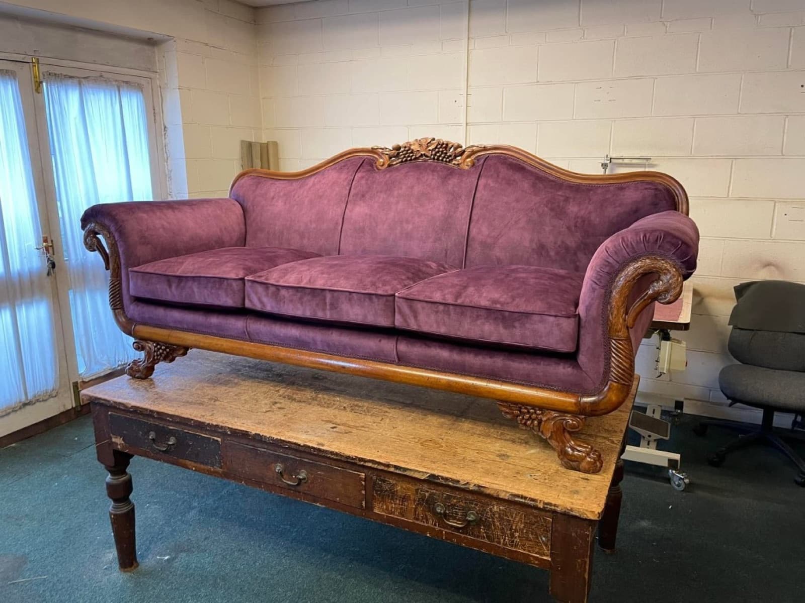 Ornate camelback three-seater sofa reupholstered in deep plum fabric