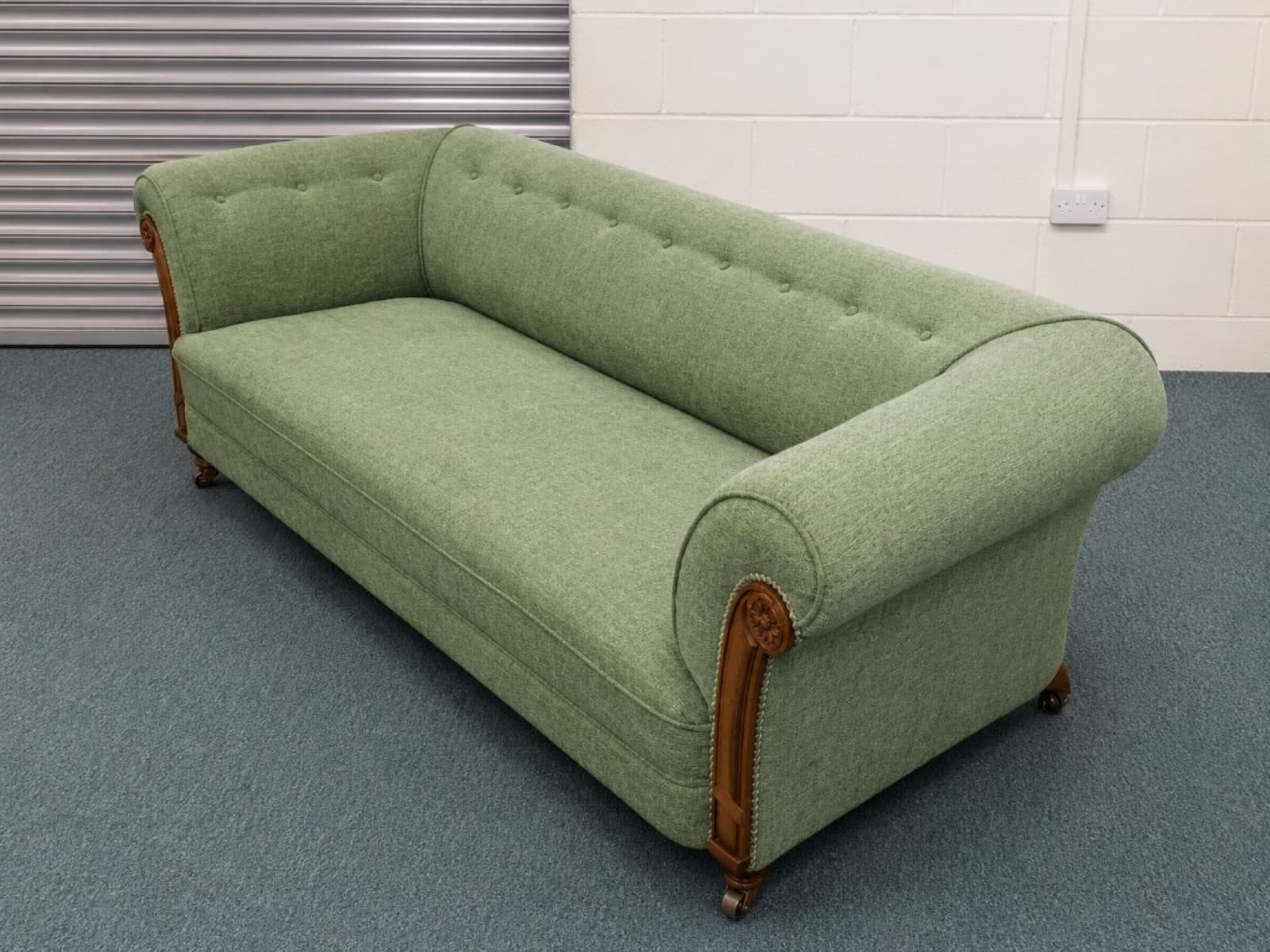 Traditional sofa reupholstered in sage green fabric with button tufting and carved wood detail